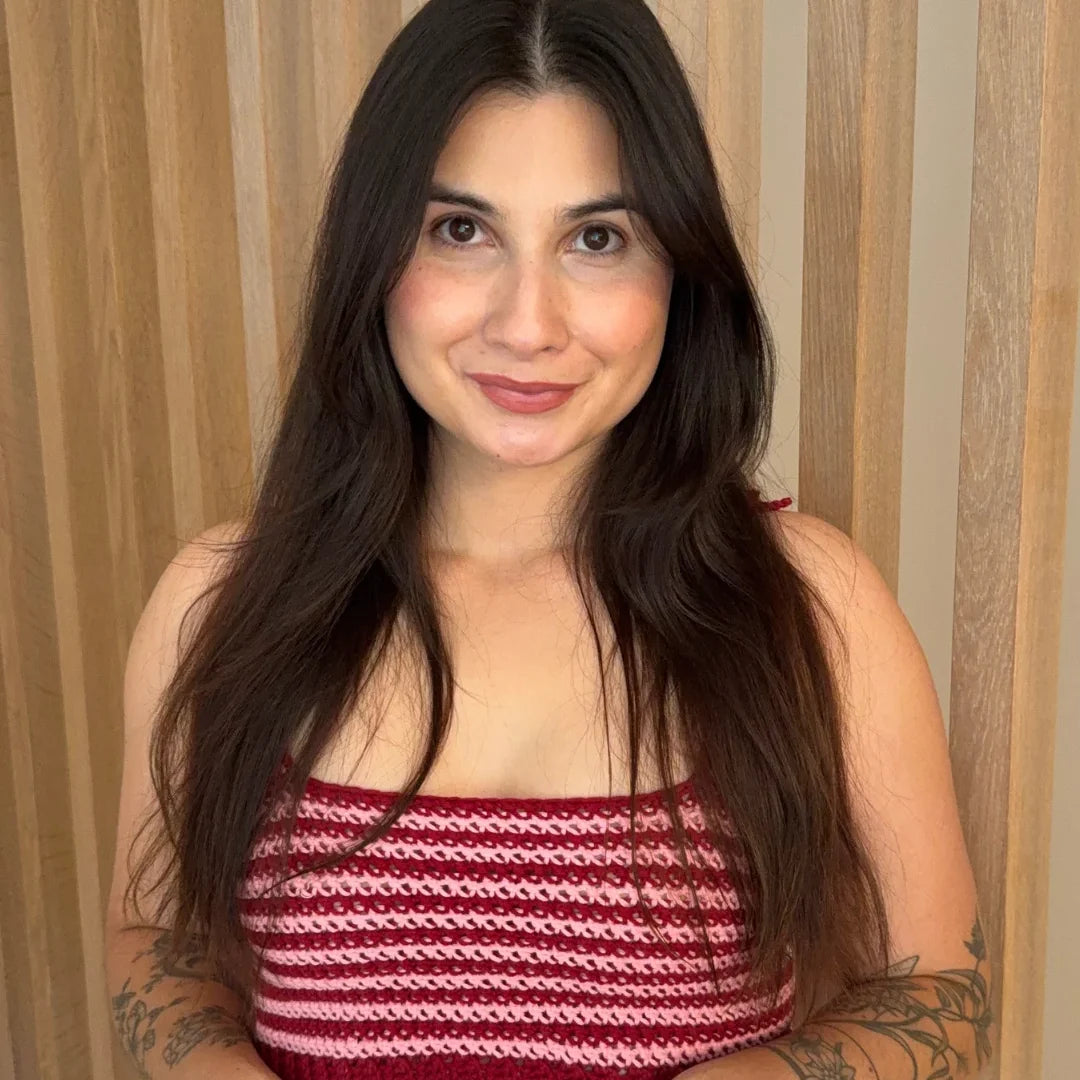 Woman with long dark hair wearing the crocheted Striped Top in red and pink stripes