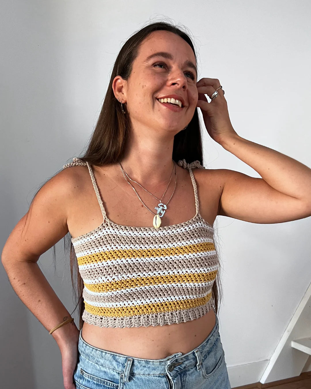 Lachende vrouw draagt gehaakte Striped Top in beige, wit en geel op jeans