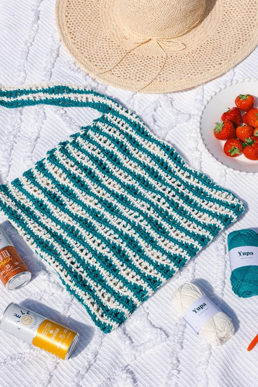 Een close-up foto van de groen met witte Beach Bag van Haakspot inclusief de garen van Yupa Eco Cotton.