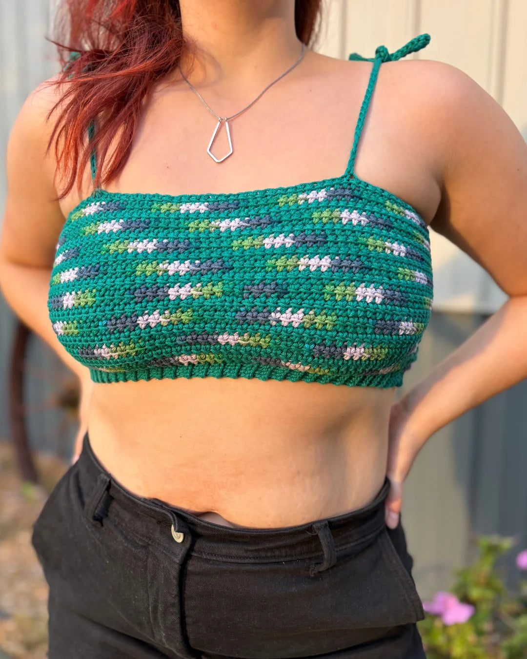 Vrouw draagt gehaakte Striped Top in groentinten met spikkels, gecombineerd met zwarte jeans.