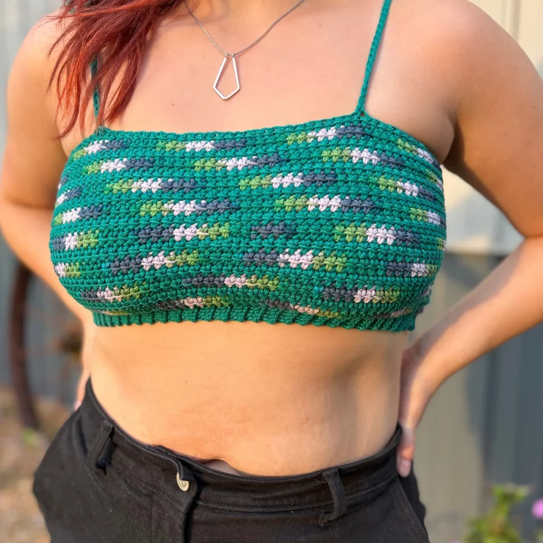 Vrouw draagt gehaakte Striped Top in groentinten met spikkels, gecombineerd met zwarte jeans.