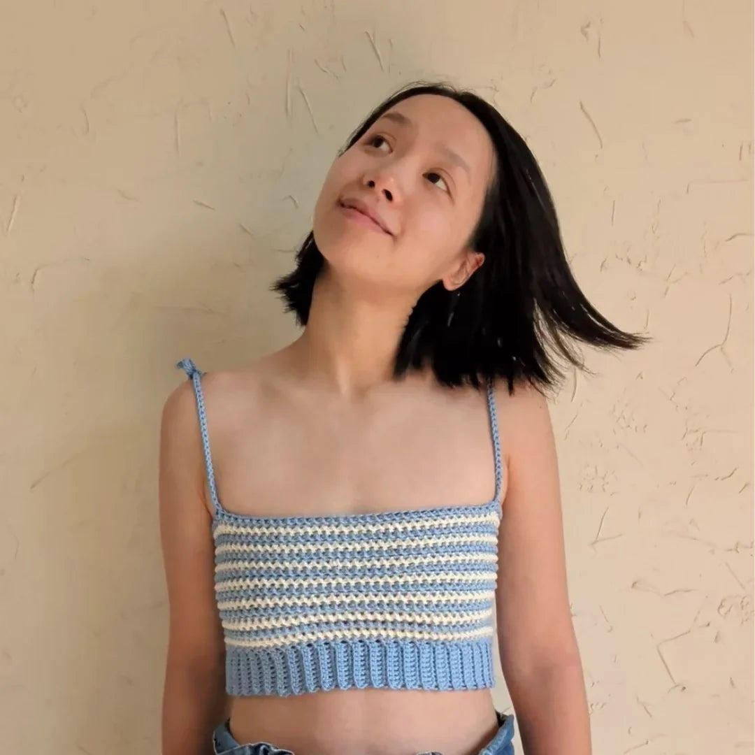 Vrouw draagt gehaakte Striped Top in blauw en ecru, gecombineerd met een jeans broek